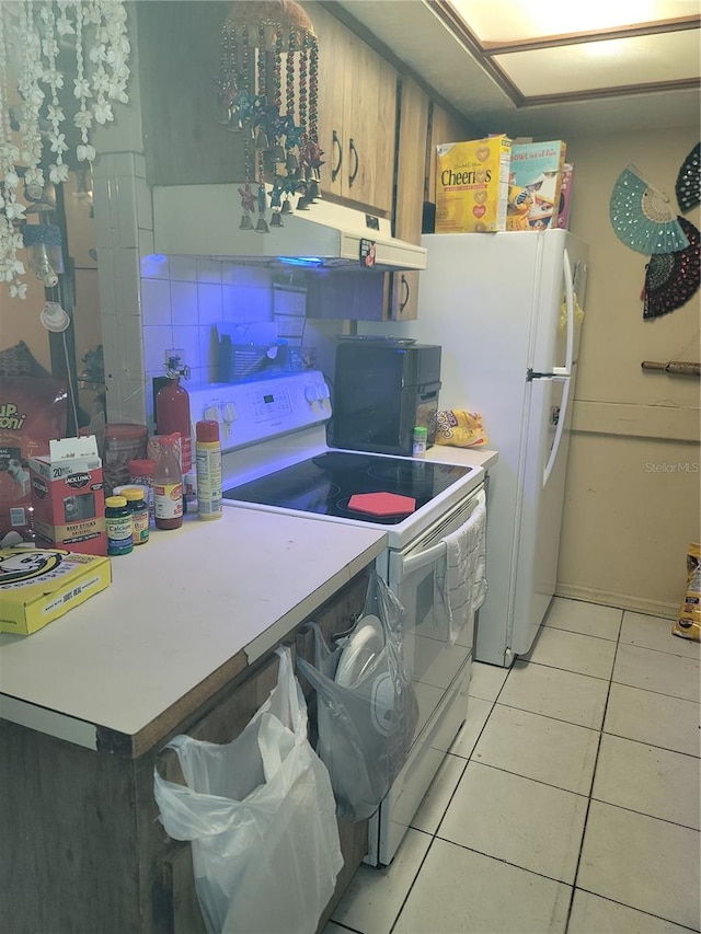 kitchen with light tile flooring, backsplash, white appliances, and wall chimney range hood