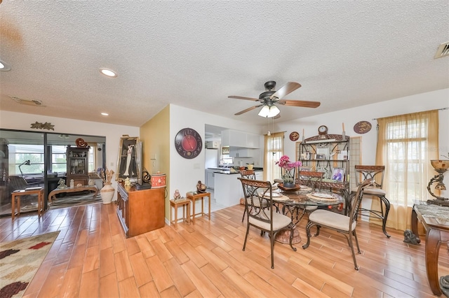 dining room with ceiling fan, light hardwood / wood-style flooring, and a textured ceiling