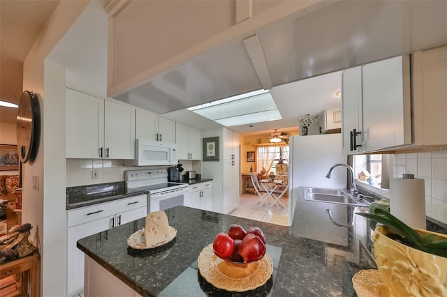 kitchen with backsplash, dark stone counters, white appliances, sink, and white cabinets