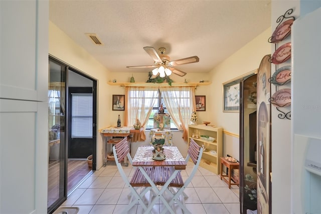 tiled dining space featuring a textured ceiling and ceiling fan