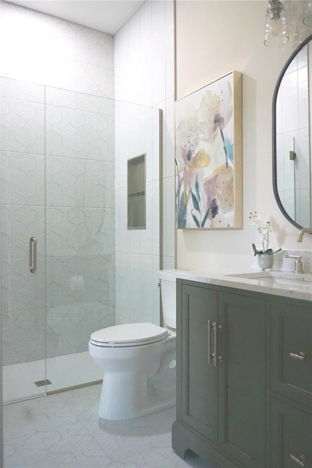 bathroom with tile patterned flooring, vanity, a shower with door, and toilet