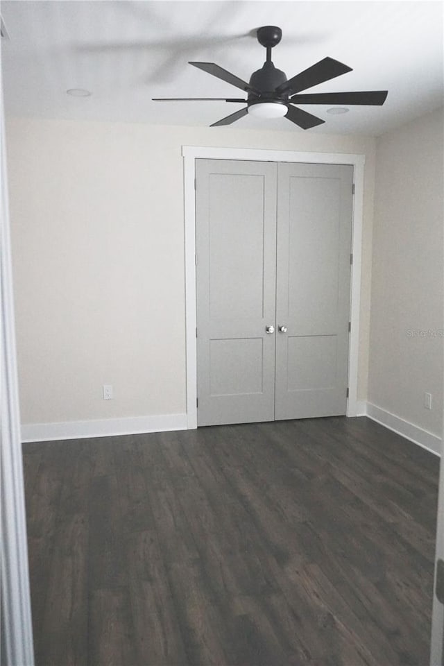 unfurnished bedroom with ceiling fan, dark wood-type flooring, and a closet