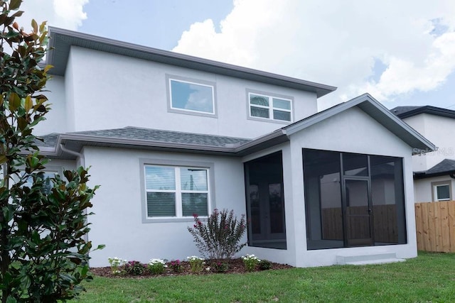 back of house featuring a sunroom and a lawn