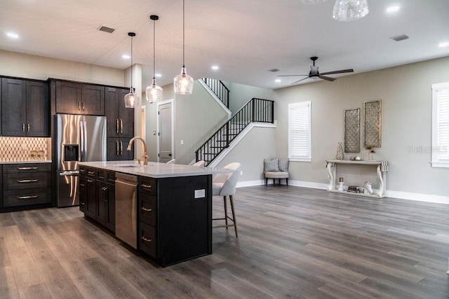 kitchen with sink, a breakfast bar area, appliances with stainless steel finishes, an island with sink, and pendant lighting