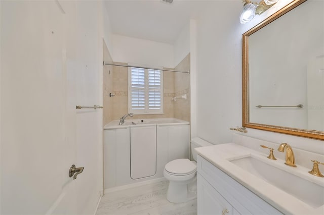 bathroom with vanity with extensive cabinet space, hardwood / wood-style flooring, and toilet