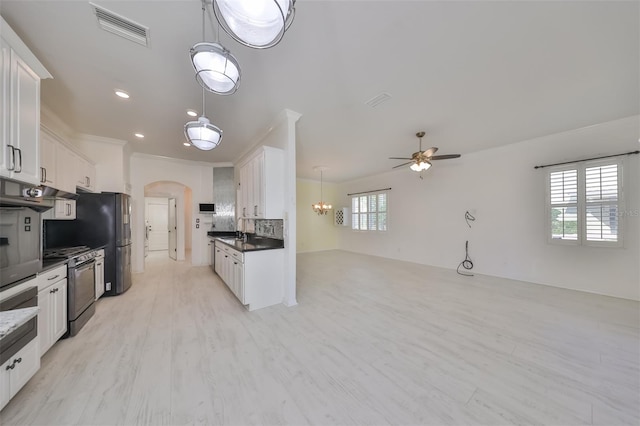 kitchen with backsplash, stainless steel range, ceiling fan with notable chandelier, white cabinetry, and pendant lighting