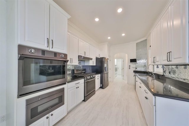 kitchen with backsplash, sink, stainless steel appliances, and white cabinets