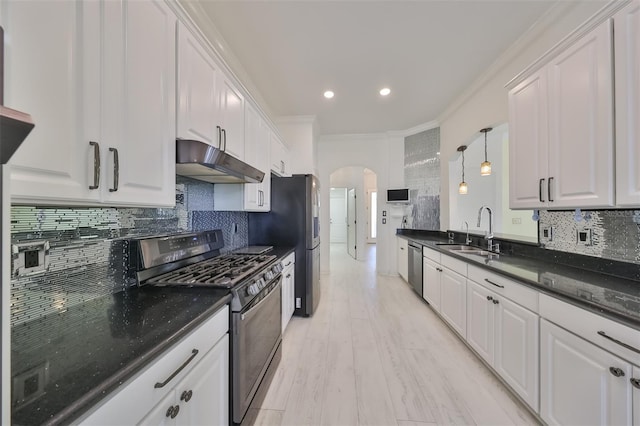 kitchen featuring gas stove, hanging light fixtures, white cabinetry, and backsplash