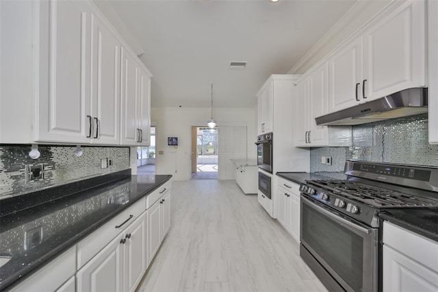 kitchen featuring backsplash, hanging light fixtures, dark stone counters, gas range, and white cabinets