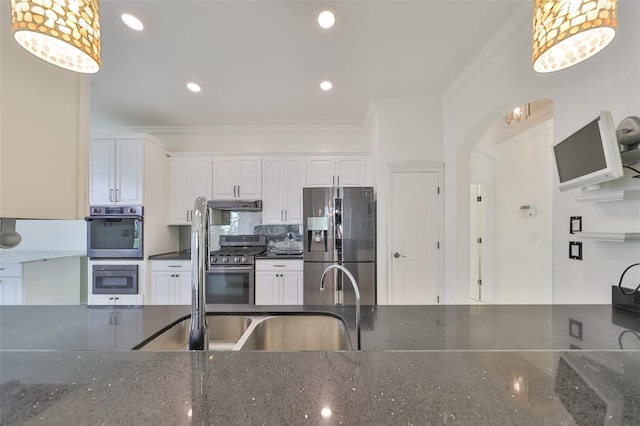 kitchen with appliances with stainless steel finishes, sink, white cabinetry, crown molding, and dark stone countertops