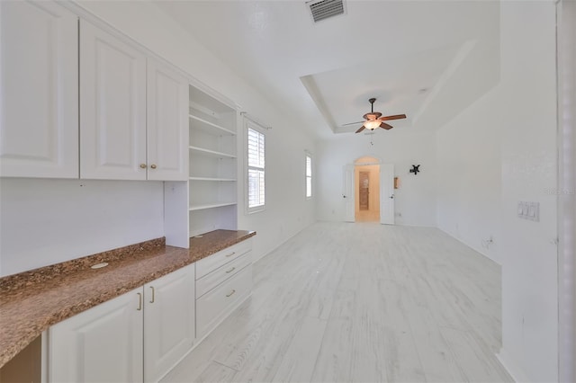 interior space featuring light hardwood / wood-style floors, ceiling fan, and a raised ceiling