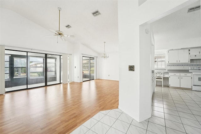 unfurnished living room with plenty of natural light, ceiling fan with notable chandelier, vaulted ceiling, and light hardwood / wood-style flooring