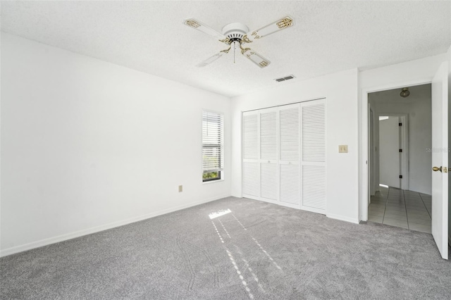 unfurnished bedroom with carpet, a textured ceiling, a closet, and ceiling fan