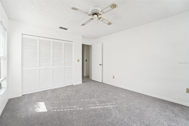 unfurnished bedroom with carpet, ceiling fan, a textured ceiling, and a closet