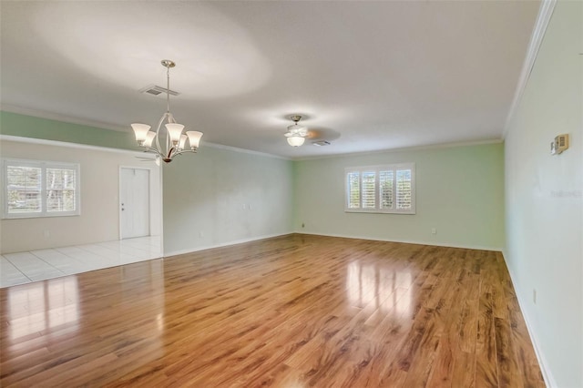 empty room featuring ornamental molding, light tile floors, and ceiling fan with notable chandelier