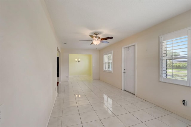 spare room featuring light tile floors and ceiling fan with notable chandelier