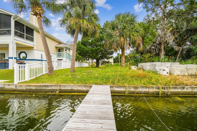 dock area with a water view, fence, and a lawn