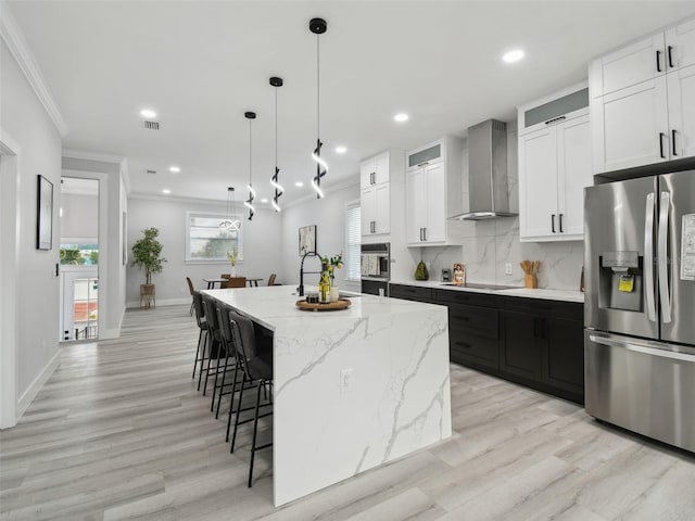 3380 Holly Springs Dr, Hernando Beach, FL 34607 - kitchen with stainless steel refrigerator with ice dispenser, wall chimney range hood, ornamental molding, a breakfast bar, and light wood-style flooring