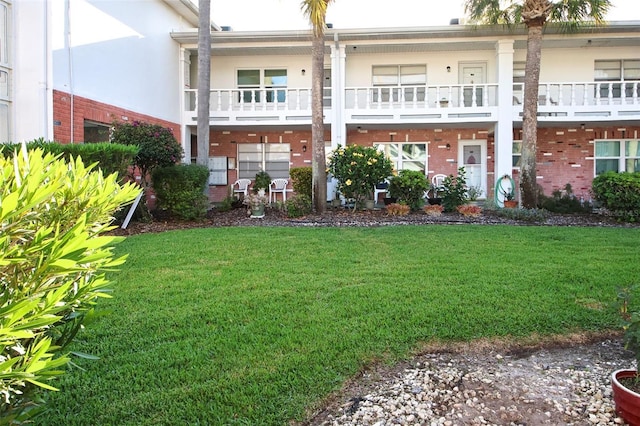 back of house featuring a balcony and a yard