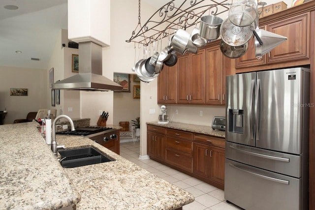 kitchen with sink, stainless steel fridge, light stone countertops, light tile patterned floors, and island exhaust hood