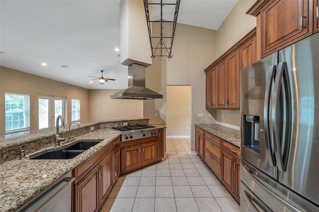 kitchen with sink, ceiling fan, range hood, light stone counters, and stainless steel appliances