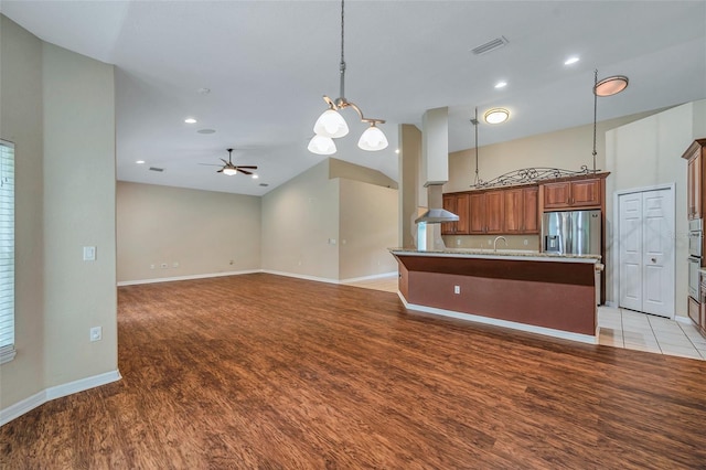 kitchen featuring stainless steel refrigerator with ice dispenser, decorative light fixtures, ceiling fan, and wall chimney exhaust hood