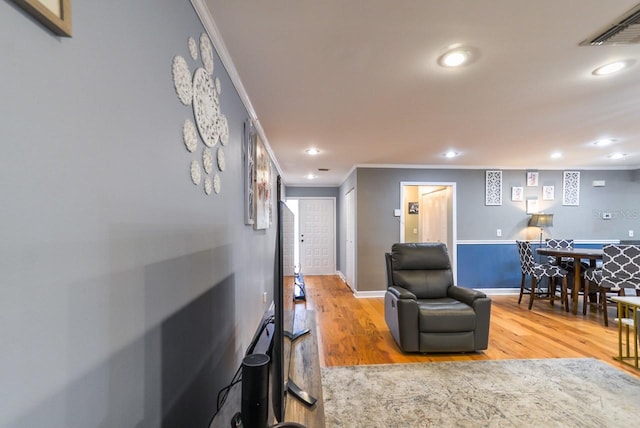 living room with ornamental molding and light hardwood / wood-style floors