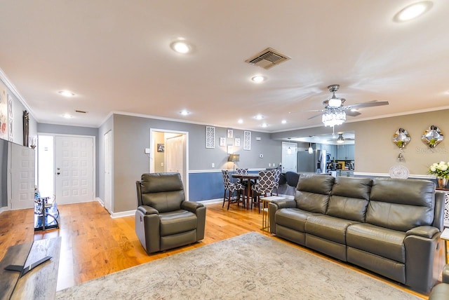 living room with ceiling fan, crown molding, and light hardwood / wood-style floors