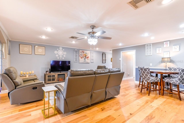 living room featuring ornamental molding, ceiling fan, and light wood-type flooring