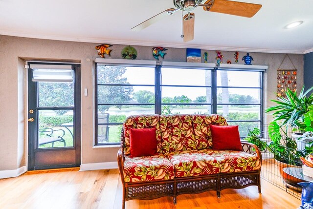 living room with light hardwood / wood-style floors, ornamental molding, and ceiling fan