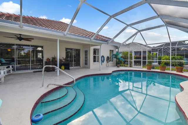 view of swimming pool featuring a patio area, glass enclosure, and ceiling fan