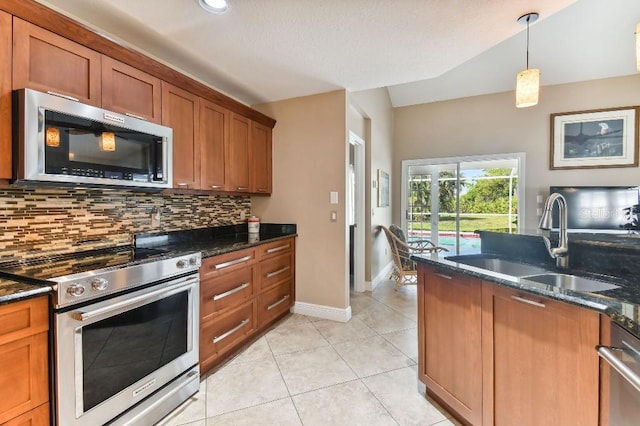 kitchen with appliances with stainless steel finishes, sink, dark stone countertops, and decorative light fixtures