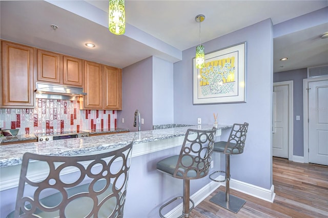 kitchen with kitchen peninsula, hanging light fixtures, and light stone countertops