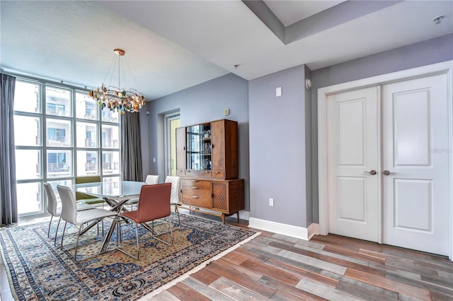 dining space with hardwood / wood-style floors, a notable chandelier, and a healthy amount of sunlight