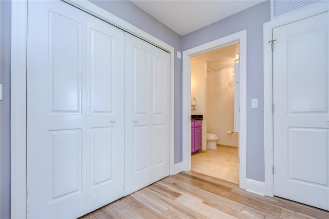 unfurnished bedroom with a closet, light wood-type flooring, and ensuite bathroom