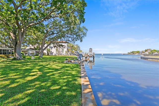 view of dock with a yard and a water view