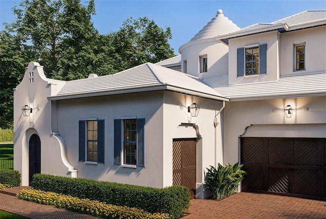 view of front of house featuring an attached garage, decorative driveway, and stucco siding