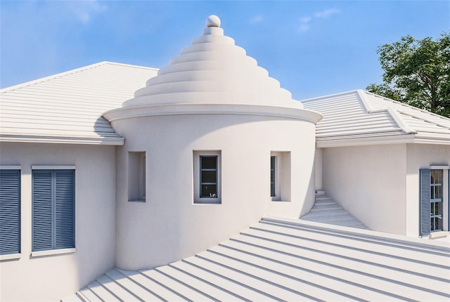 rear view of house featuring stucco siding