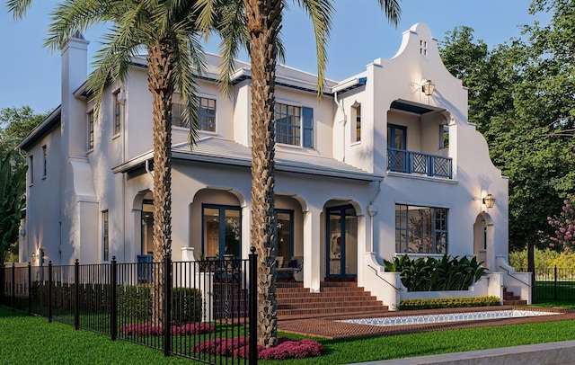 view of front of home featuring fence, a balcony, and stucco siding