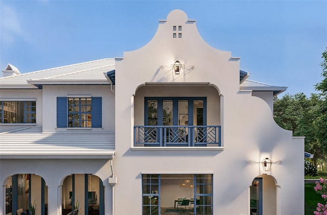 back of property featuring a balcony and stucco siding