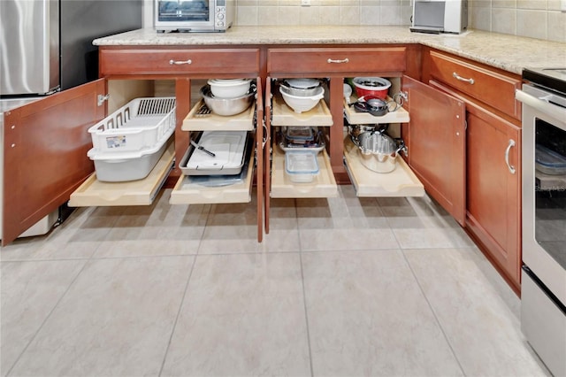 kitchen featuring stainless steel fridge, tasteful backsplash, light tile floors, and light stone counters