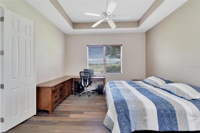 bedroom with a raised ceiling, ceiling fan, and hardwood / wood-style flooring