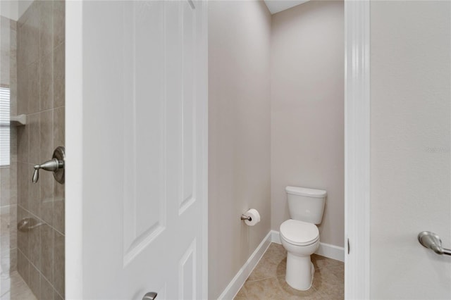 bathroom featuring toilet, tiled shower, and tile flooring