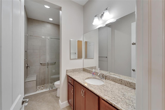 bathroom with tile flooring, toilet, large vanity, and tiled shower