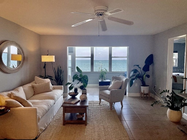 living room with tile floors, ceiling fan, and a water view