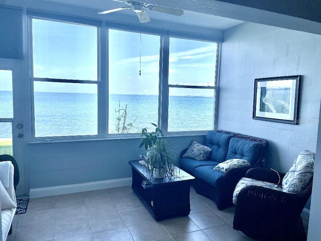 living room featuring a water view, ceiling fan, and light tile floors