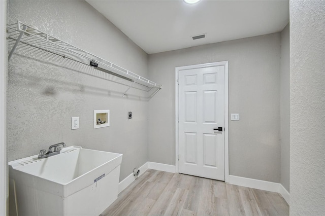 laundry area with washer hookup, hookup for an electric dryer, sink, and light wood-type flooring