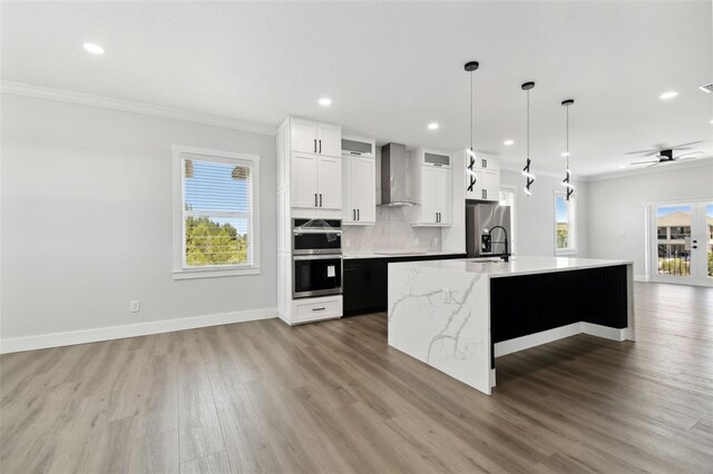 3230 Azalea Dr Lot 13, Hernando Beach, FL 34607 - kitchen with wall chimney exhaust hood, stainless steel appliances, a center island with sink, light wood-style floors, and ornamental molding
