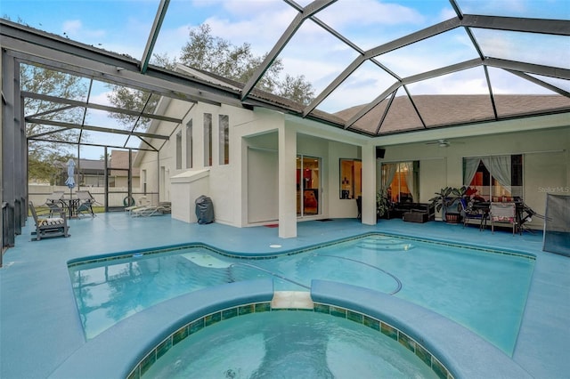 view of swimming pool featuring glass enclosure, ceiling fan, an in ground hot tub, and a patio