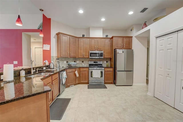 kitchen with dark stone counters, sink, tasteful backsplash, decorative light fixtures, and stainless steel appliances